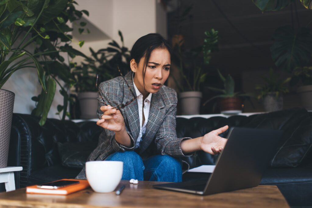 Puzzled copywriter in smart casual wear solwing web problems with publication browsed on modern netbook technology, serious freelance woman confused with received email news on laptop