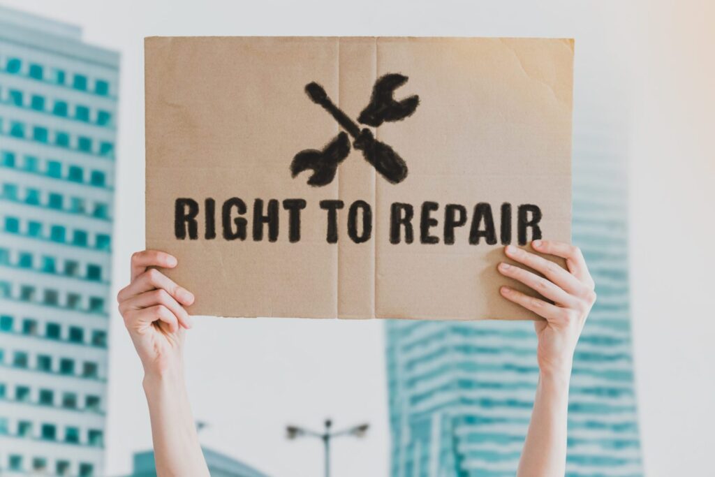 The phrase " Right to repair " and repair icon drawn on a carton banner in men's hand. Human holds a cardboard with an inscription. Product fixing. Fix a product. Guarantee. Client service. Consumers