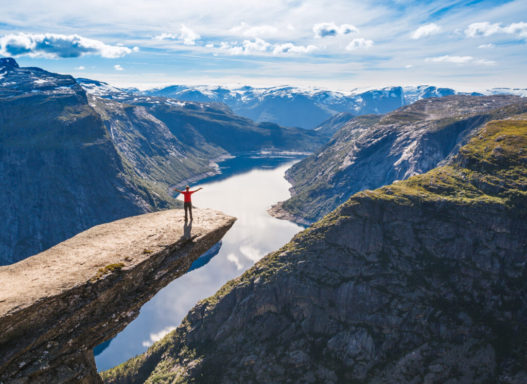 Norwegian landscape showing person standing at Trolltunga looking out over the fjord and mountains